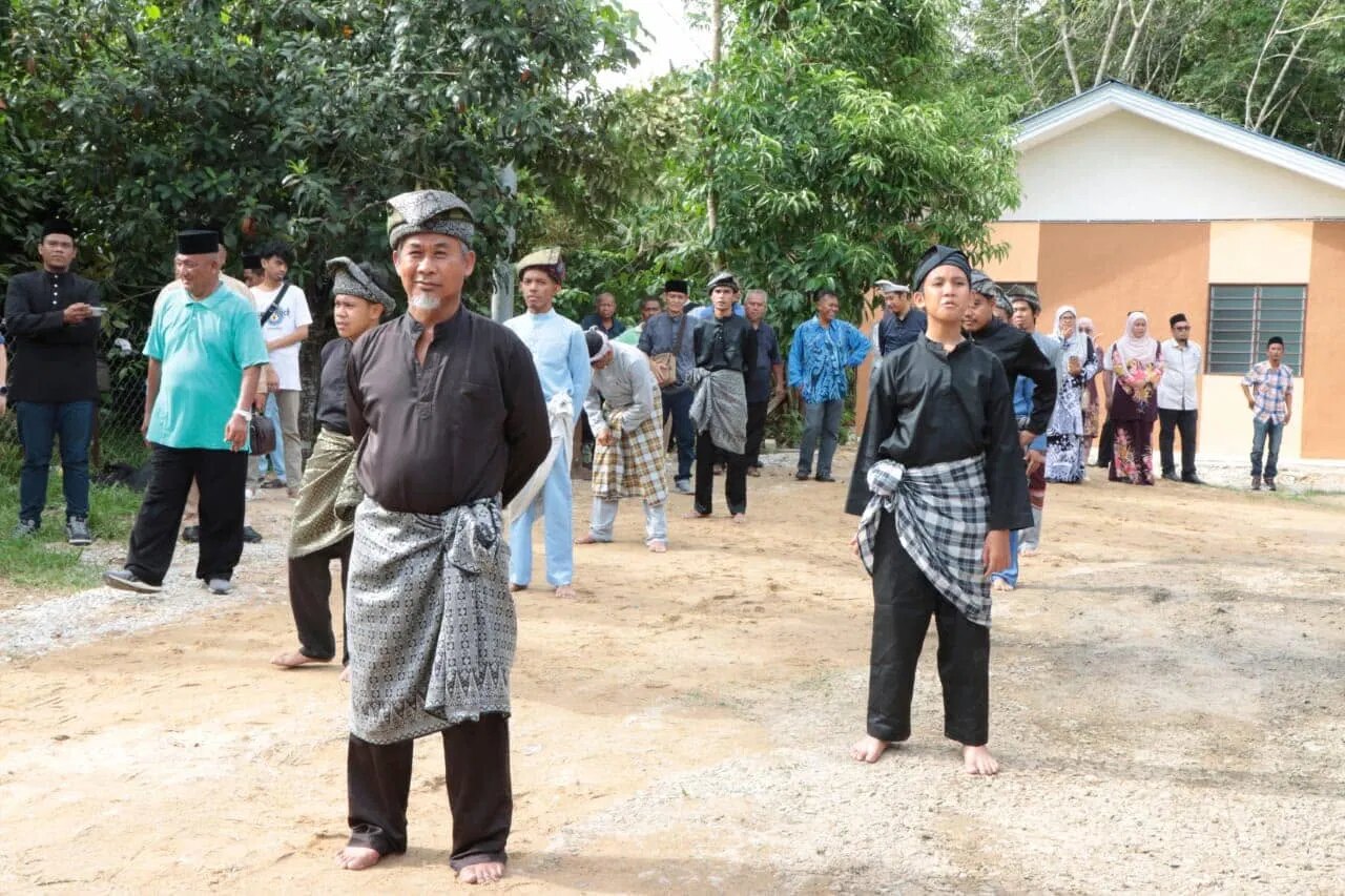 Seorang guru dan murid muda bersedia di halaman laman warisan.